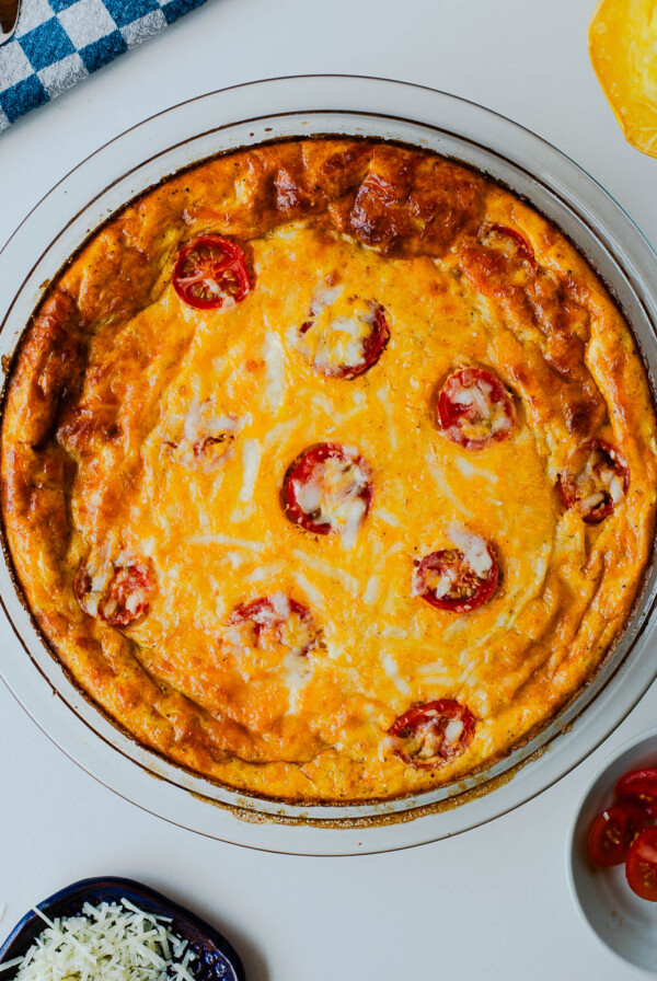 Baked spaghetti squash crustless quiche golden brown with melted cheese and roasted tomatoes