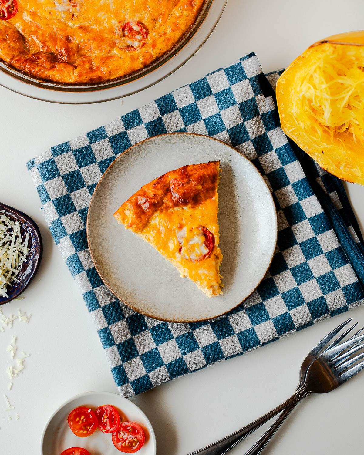 Top view of a slice of spaghetti squash crustless quiche styled on a plate with fresh ingredients