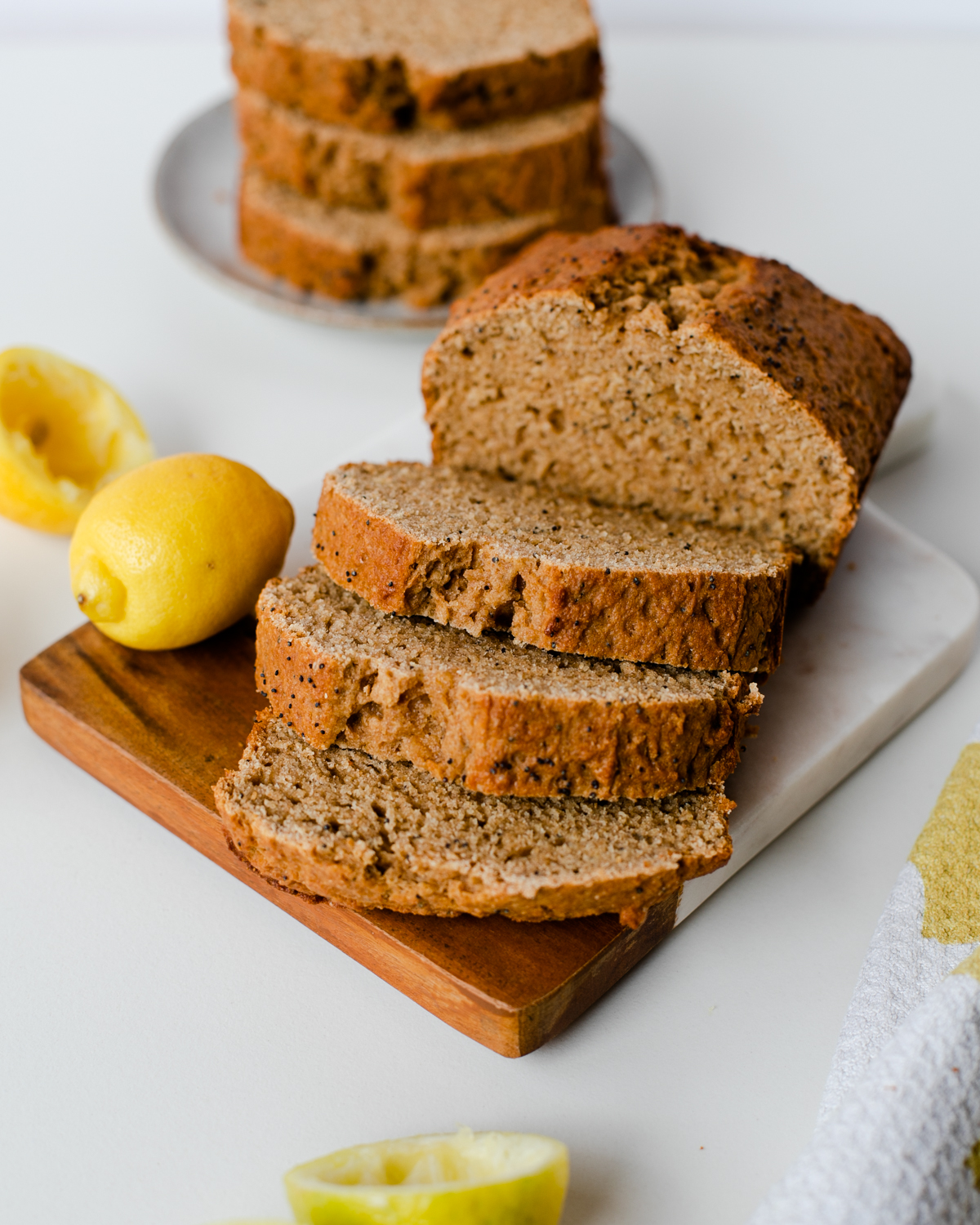 Sliced lemon poppy seed bread on cutting board with lemons, ready to serve