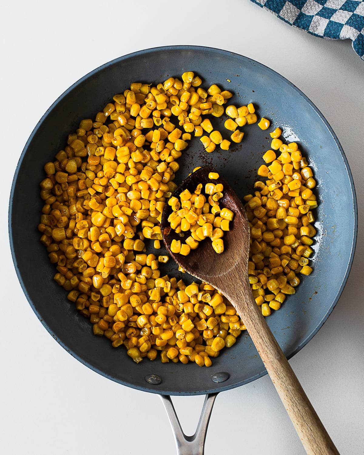 Charred corn kernels cooking in a skillet with garlic and seasonings, creating the flavorful base for easy Mexican street corn salad.