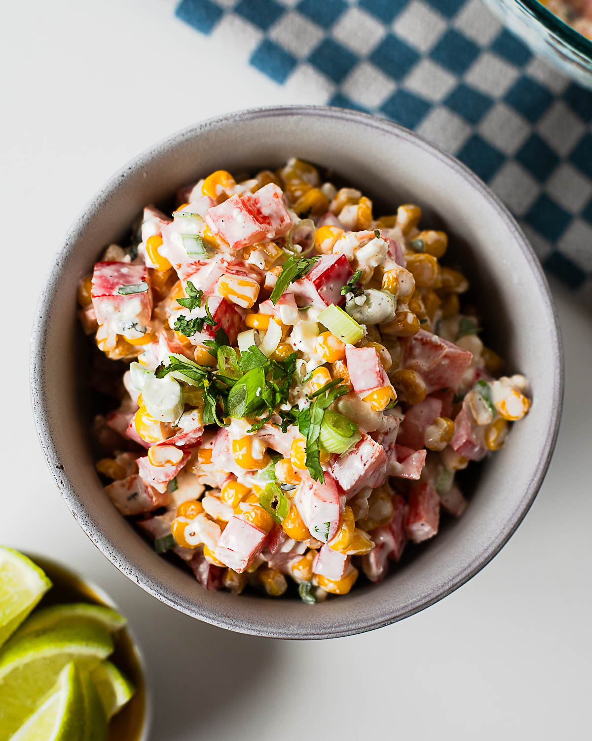 Homemade Mexican corn salad with charred corn, crisp bell peppers, creamy dressing, and cotija cheese served in a ceramic bowl.