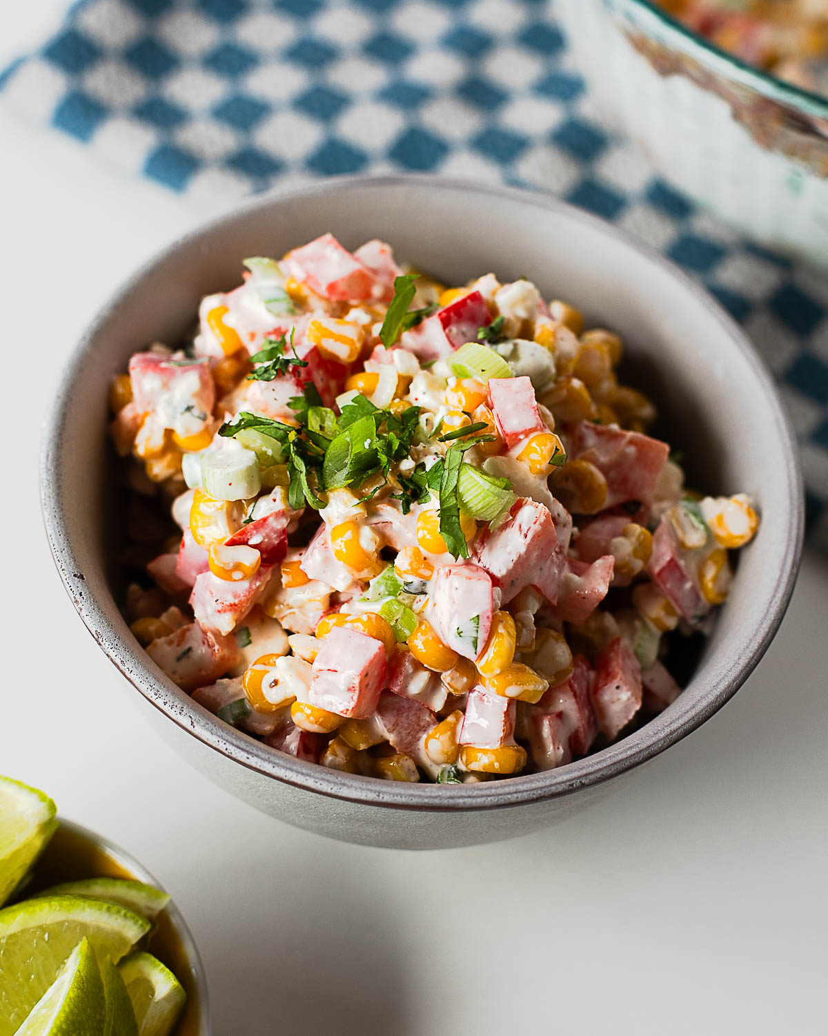 A bowl of creamy Mexican street corn salad made with sweet corn, red bell pepper, green onions, cotija cheese, and a tangy lime dressing.