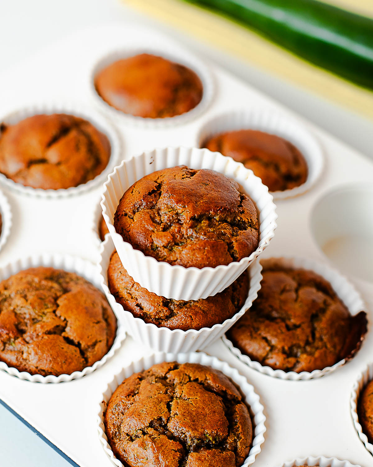 Close-up of baked almond butter zucchini muffins stacked in a silicone liner