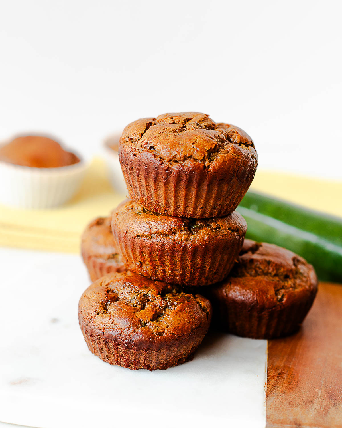 Almond butter veggie muffins piled on a serving board with fresh zucchini behind them