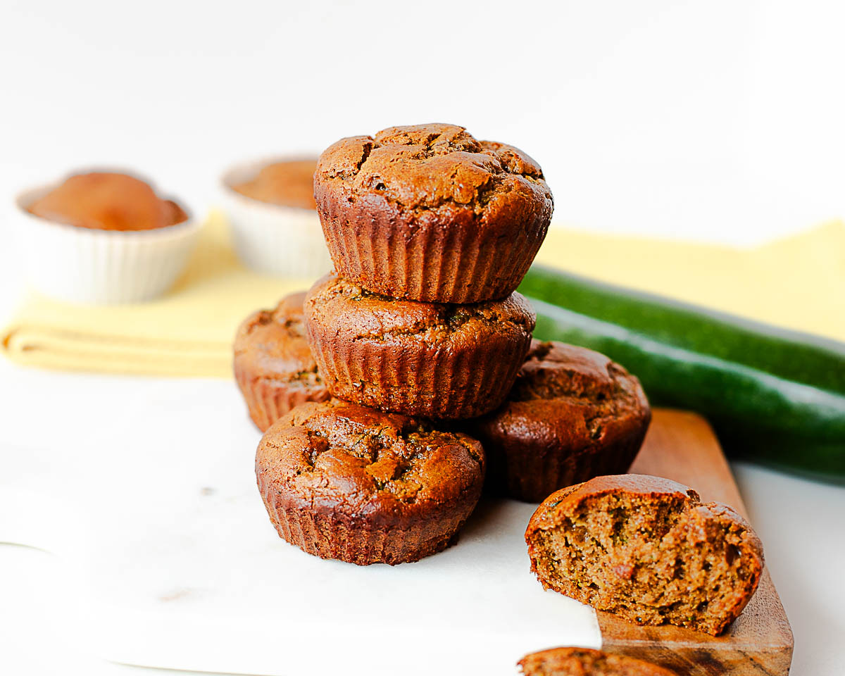 Almond butter zucchini muffins with one split open showing the moist interior