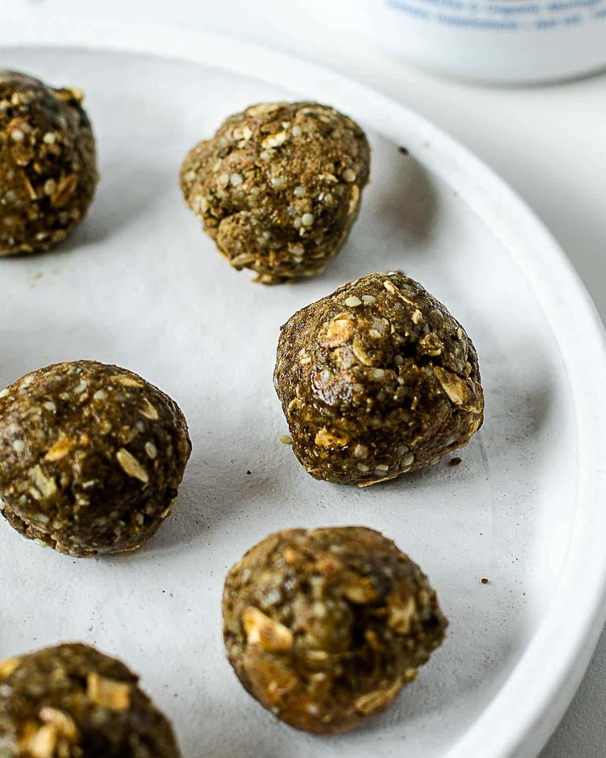 Close-up of homemade no-bake matcha protein balls with rolled oats, hemp hearts, and almond butter.