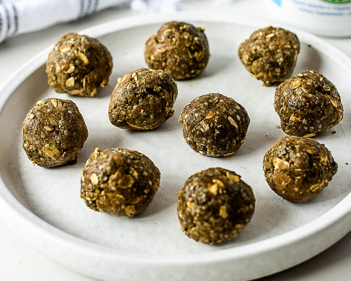 Matcha protein balls stacked on a white plate showing the chewy oat texture and green matcha color.