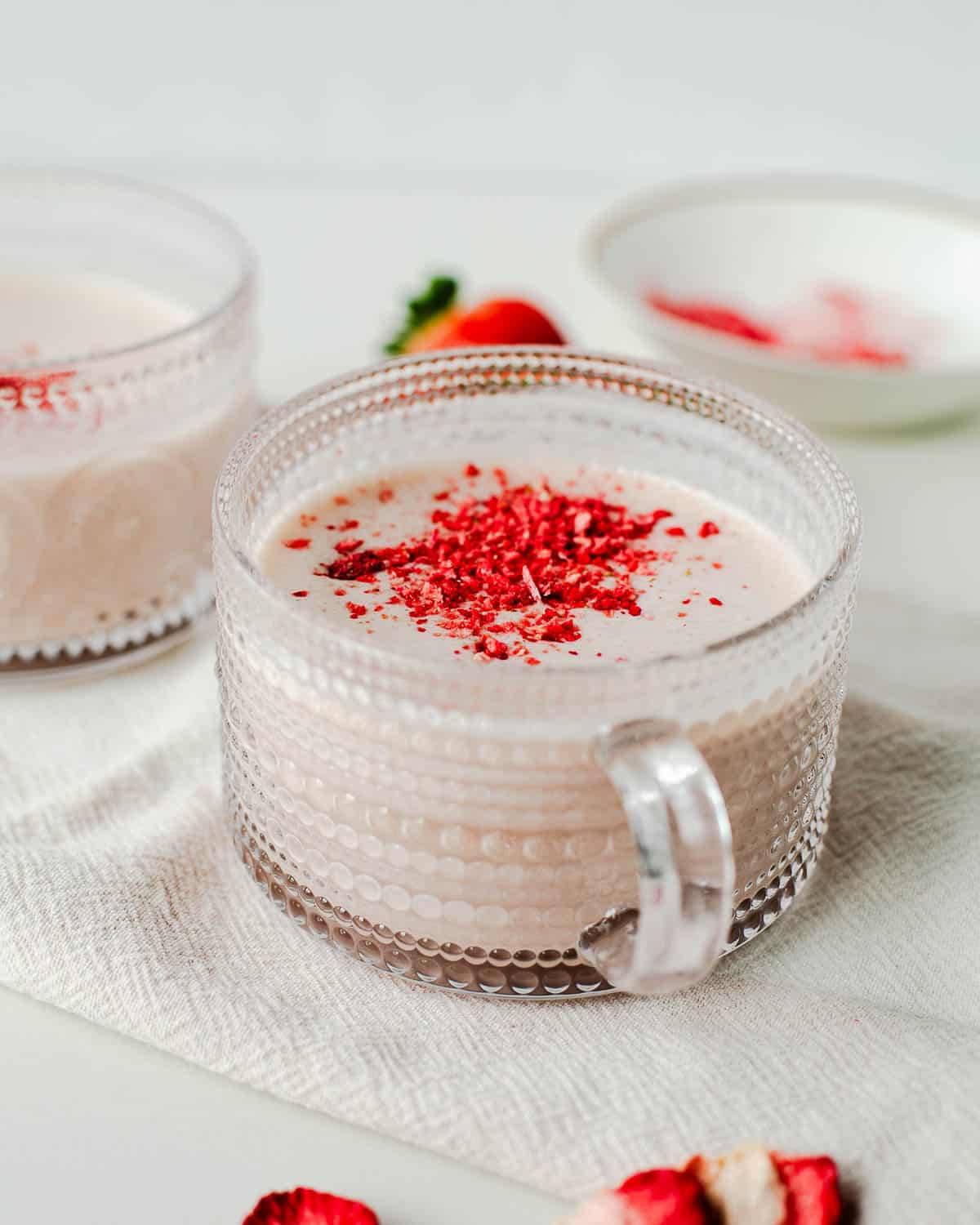 a cup of creamy dairy free strawberry hot chocolate with crushed freeze dried strawberries