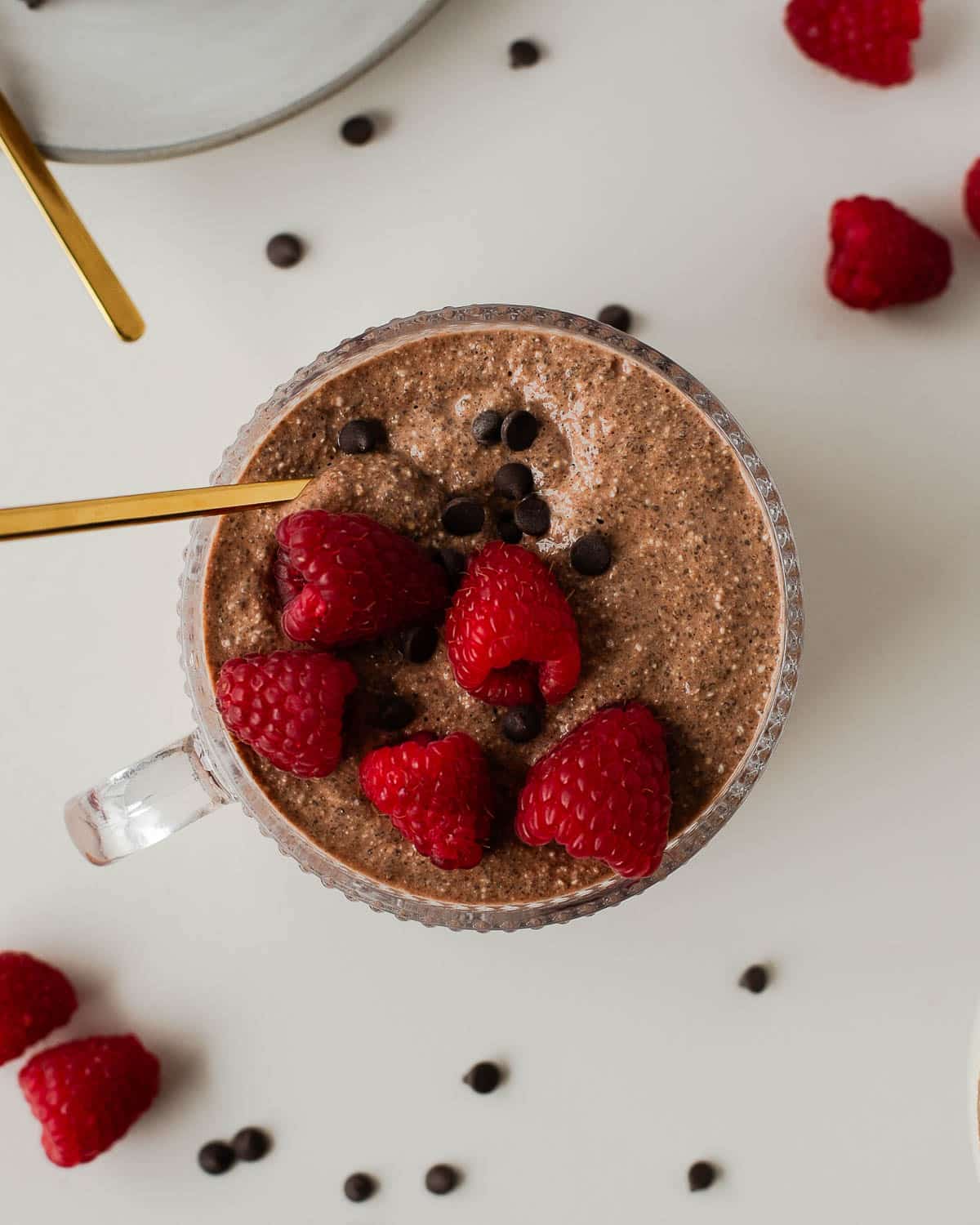 Top view of blended chocolate overnight oats topped with raspberries and dark chocolate chips.