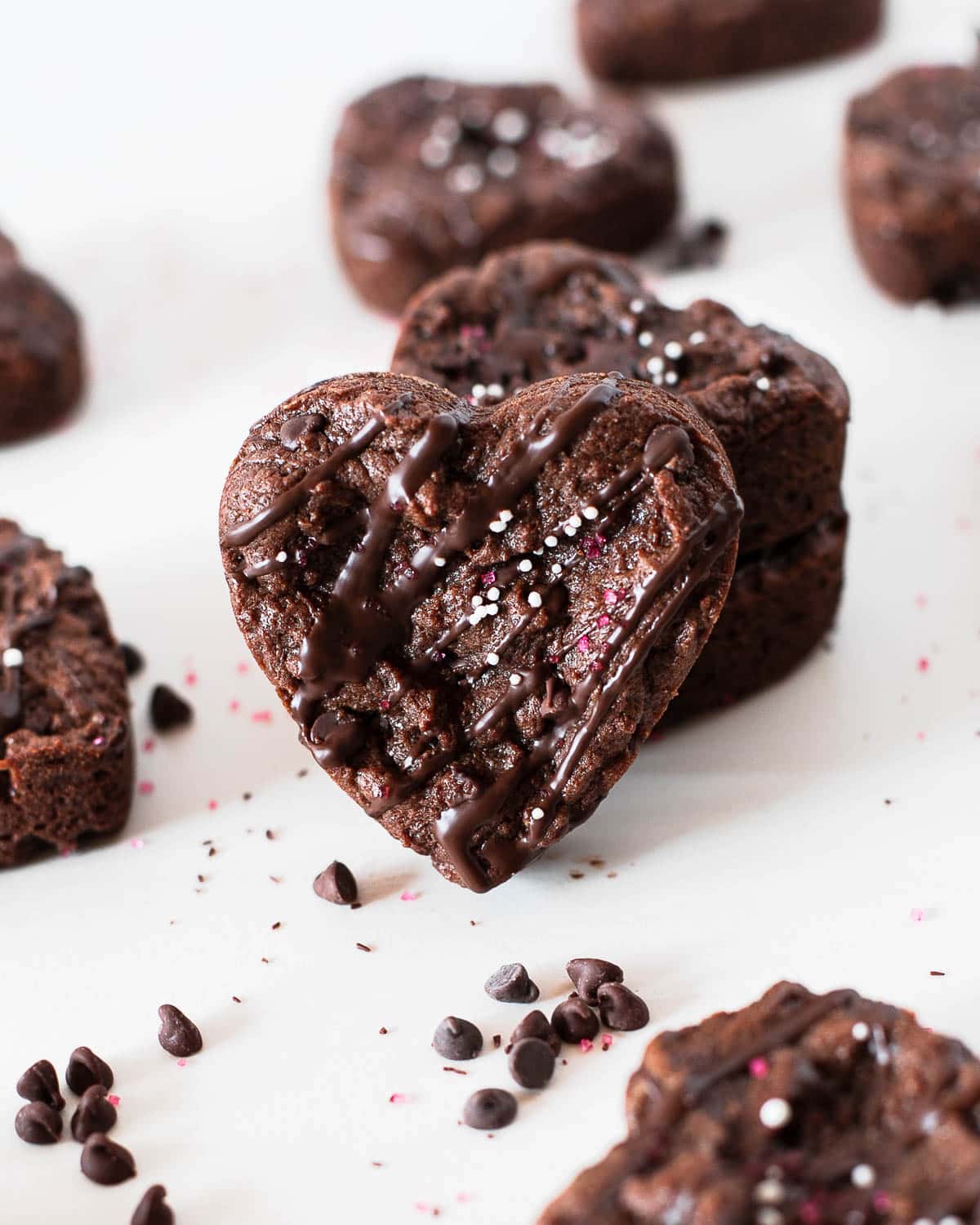 heart shaped protein brownies with chocolate chips around on a white surface.