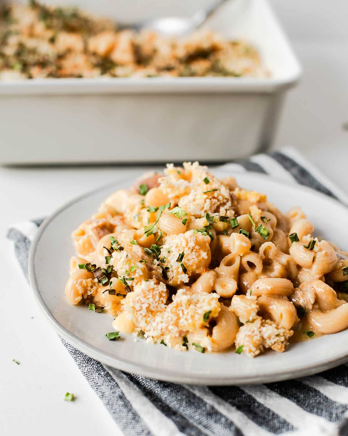 serving of tuna mac and cheese on a white plate with casserole dish in background