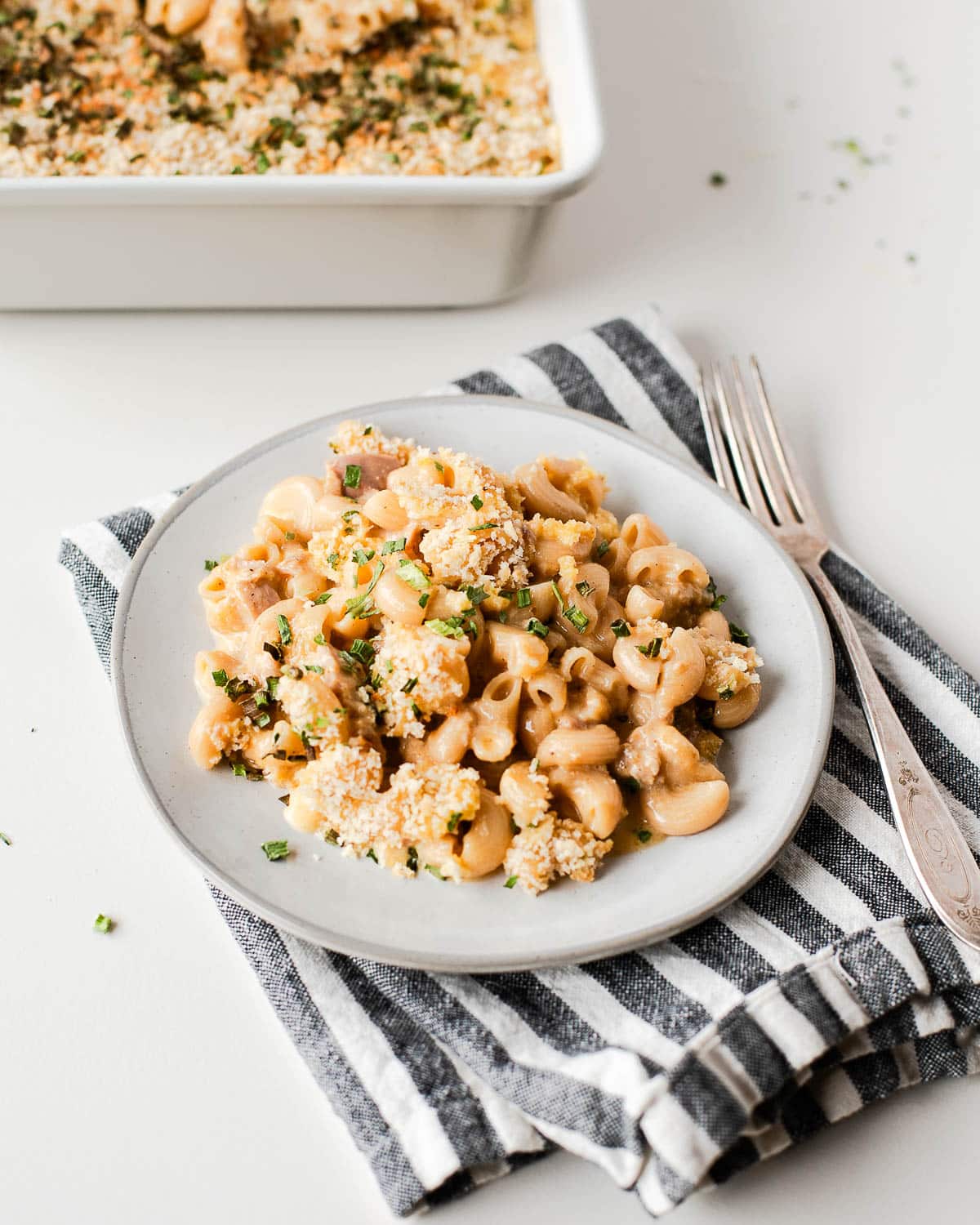 tuna macaroni and cheese on a white plate with a fork next to it