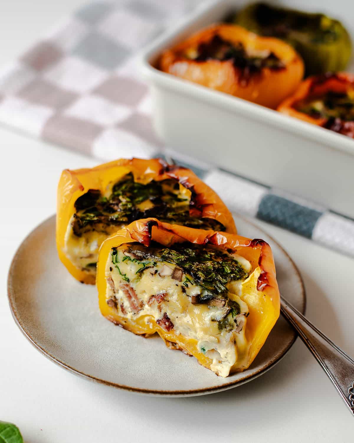 Sliced yellow bell pepper stuffed with eggs, spinach, mushrooms, and turkey bacon.