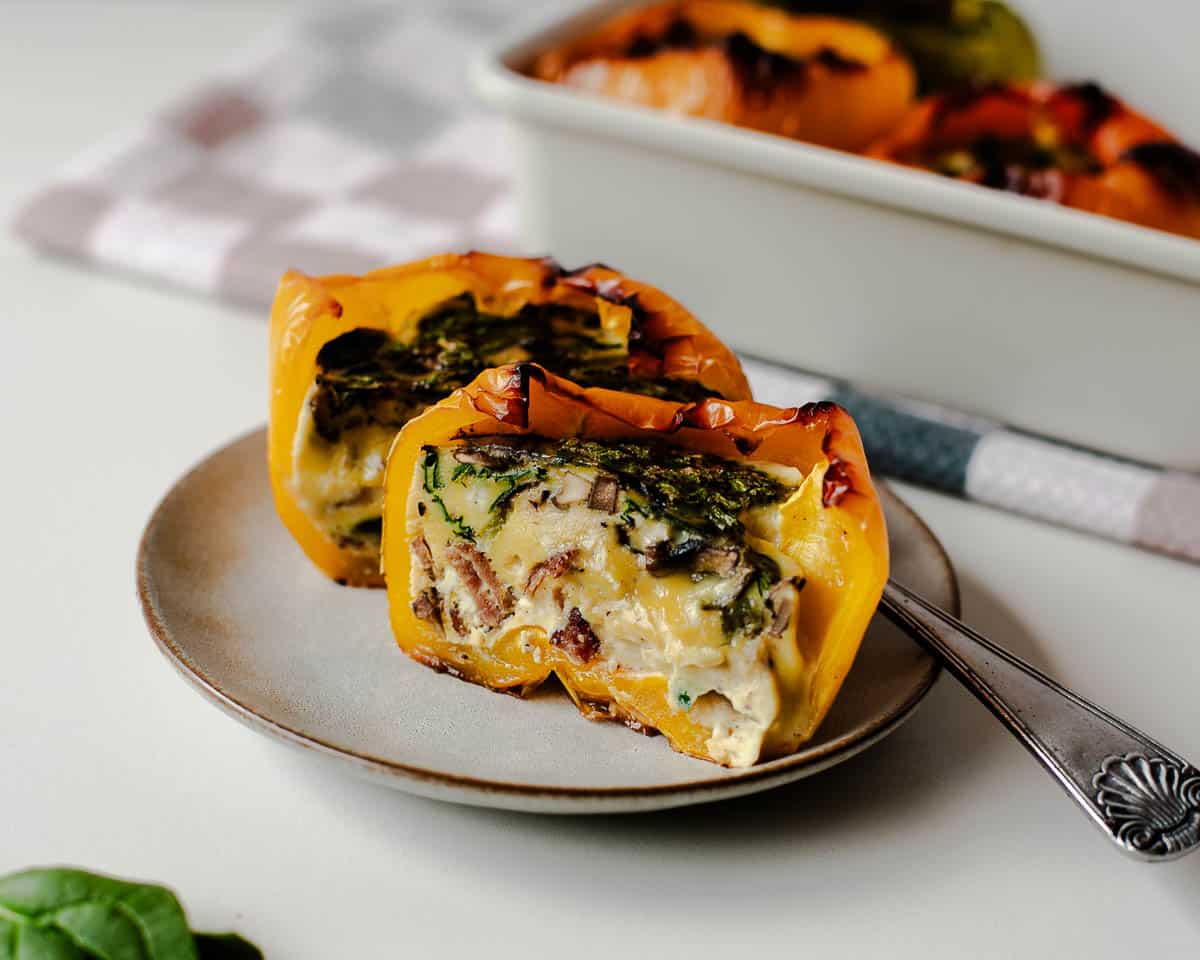 Cross-section of egg stuffed pepper on a plate showing fluffy eggs and greens.