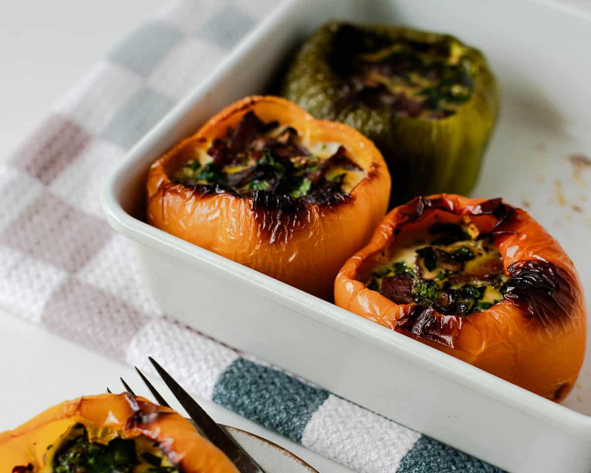 Baking dish of roasted egg stuffed bell peppers fresh from the oven.