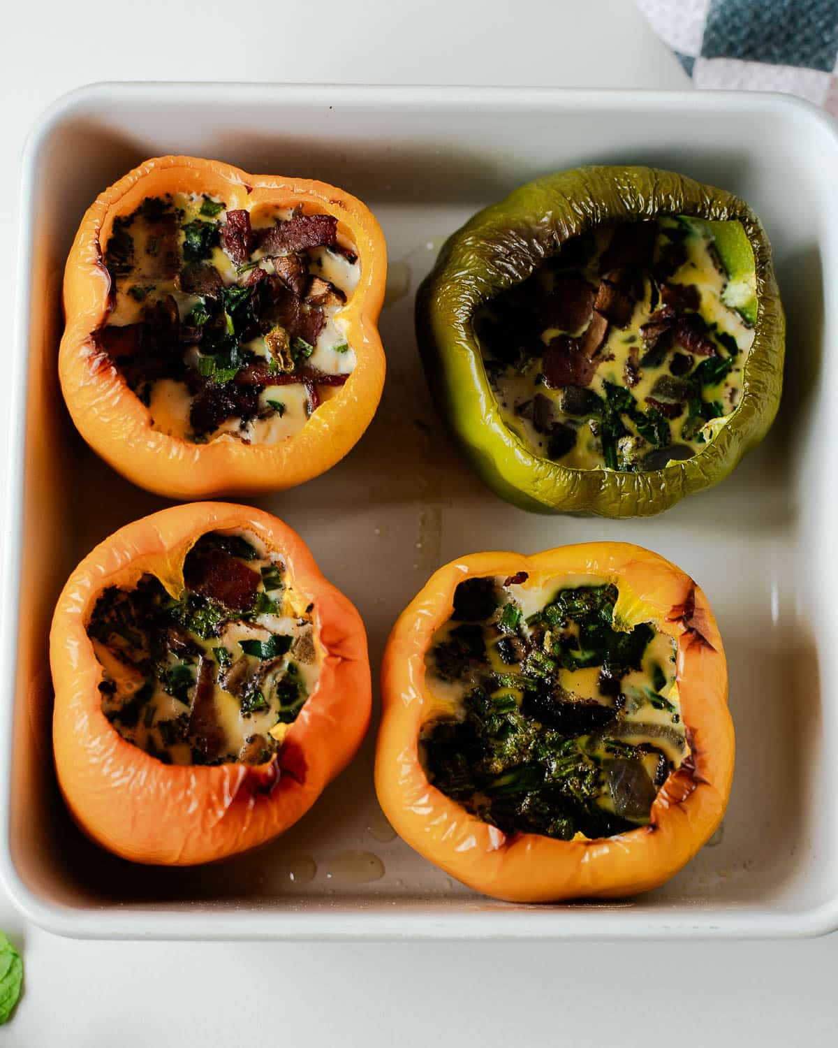 Baked breakfast egg stuffed peppers with set, golden tops in a baking dish.