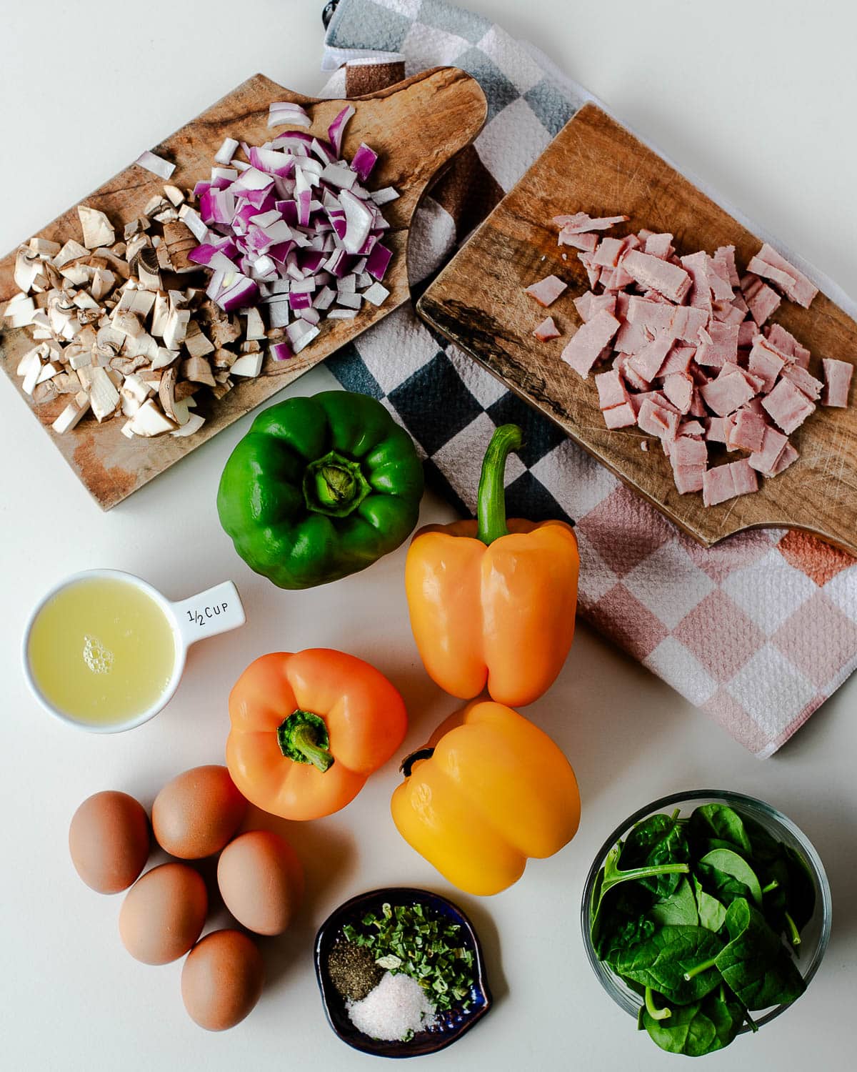 Ingredients for egg stuffed peppers—bell peppers, eggs, liquid egg whites, bacon, mushrooms, onion, spinach, chives.