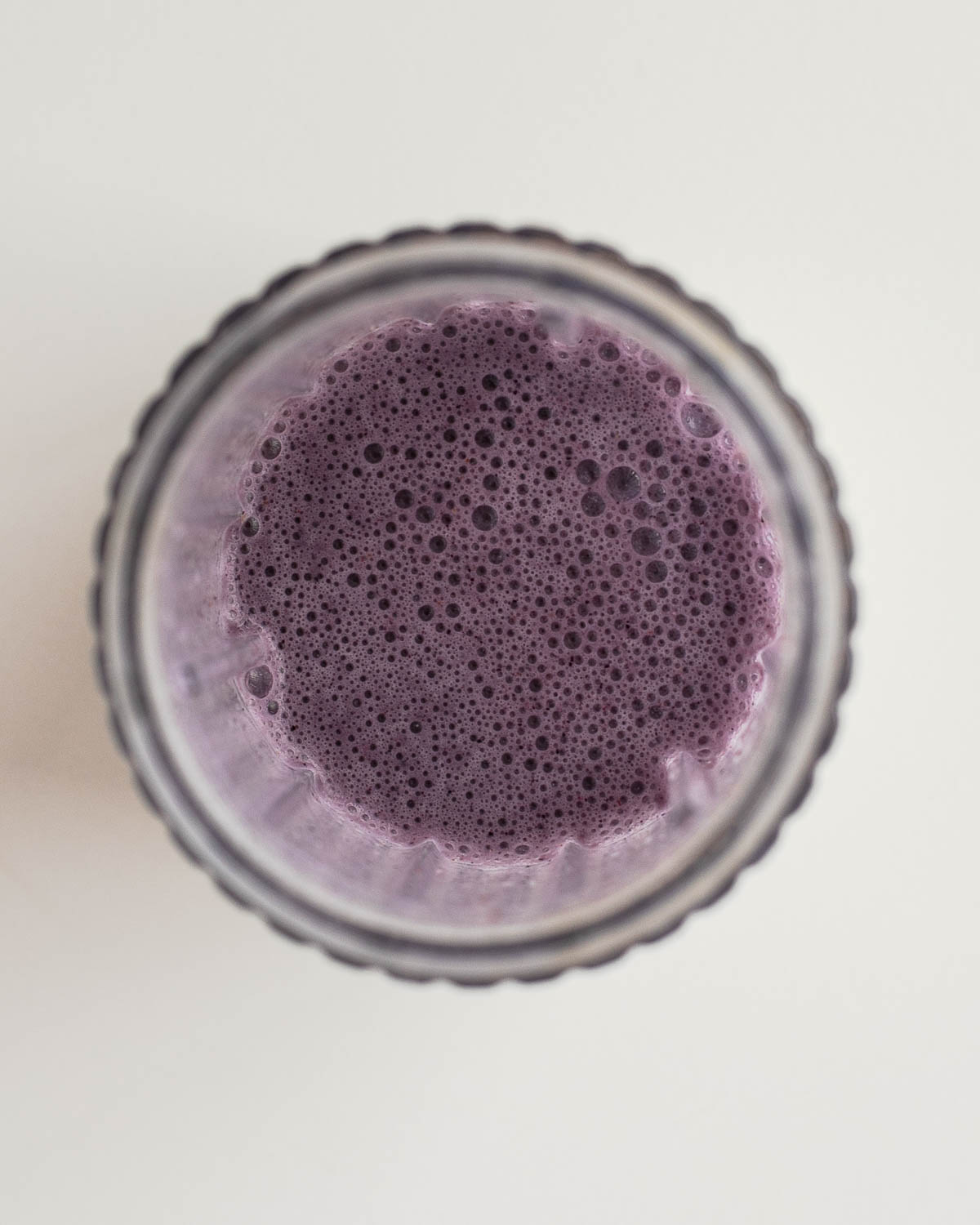 How to make this egg white smoothie recipe - blender jar filled with foamy purple egg white protein shake, top-down view.