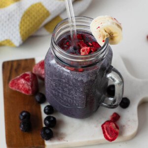 Egg white protein smoothie topped with crushed freeze-dried strawberries, banana slice on rim.