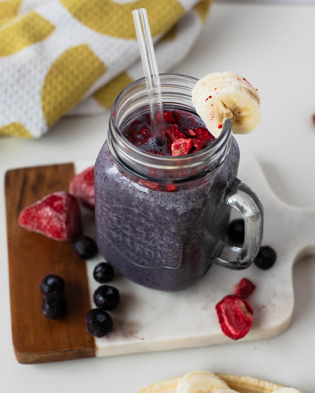 Egg white protein smoothie topped with crushed freeze-dried strawberries, banana slice on rim.