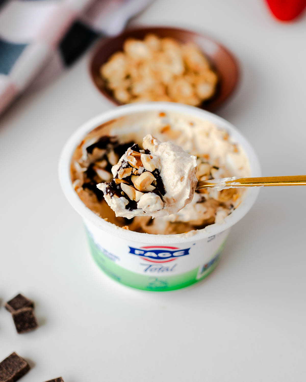 Spoonful of Snickers yogurt cup showing creamy yogurt, crisp chocolate and roasted peanut pieces.