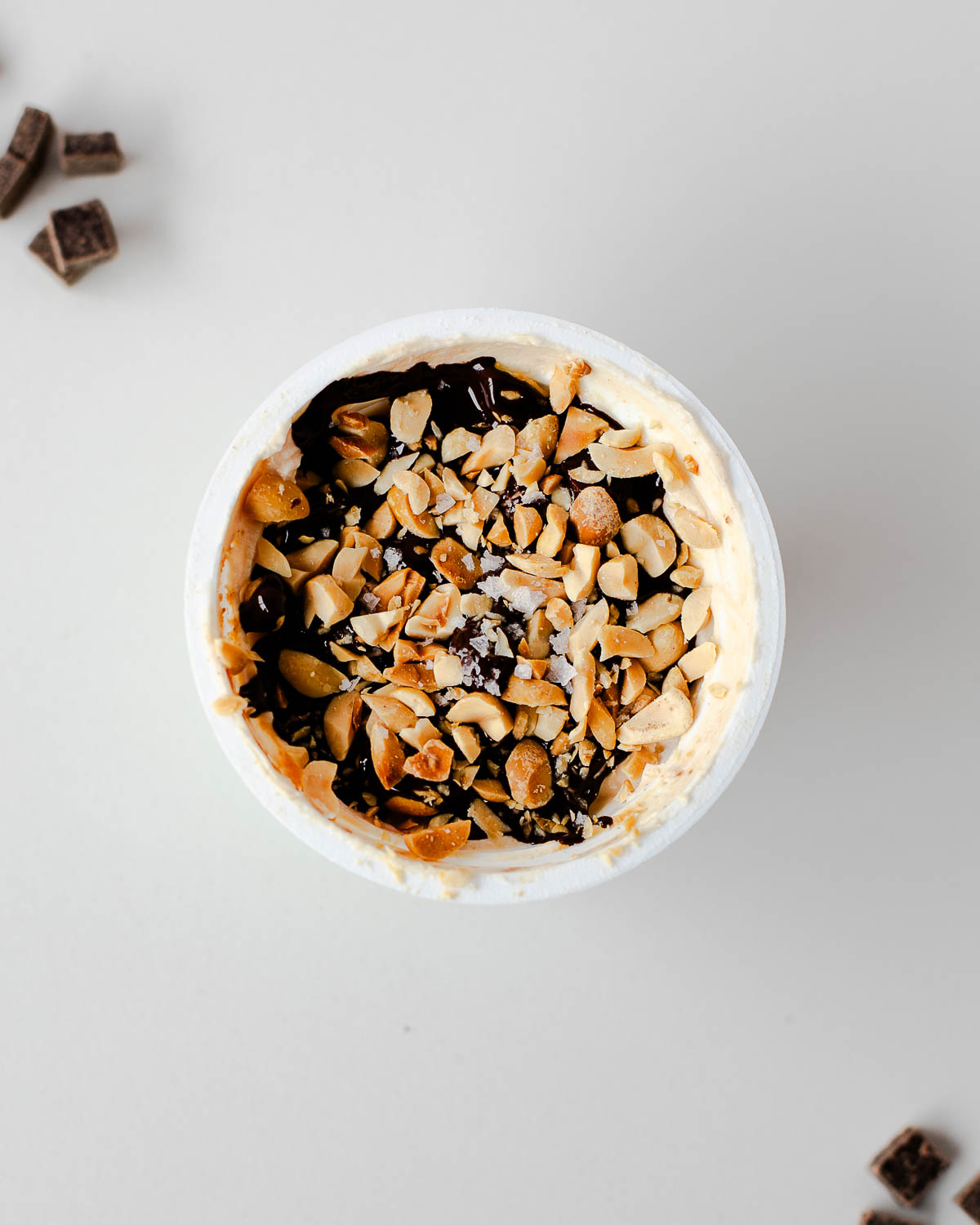 Greek yogurt cup topped with melted dark chocolate, chopped peanuts and flaky salt—Snickers yogurt cup.
