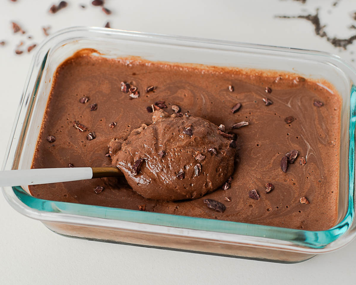 Finished chocolate protein chia pudding in glass container, sprinkled with cacao nibs.