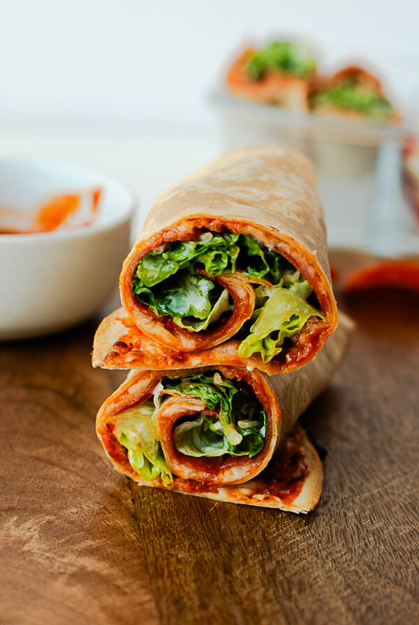 Rolled pepperoni pizza Caesar wrap sliced to show lettuce and cheese inside