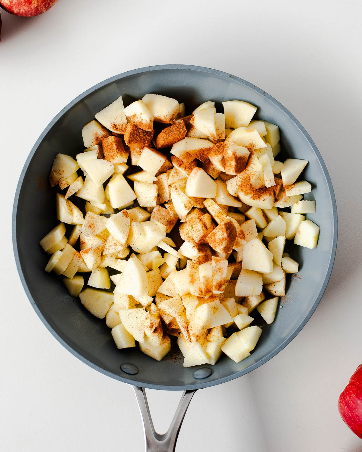 Freshly diced apples sprinkled with cinnamon in a skillet before cooking for the apple pie topping.