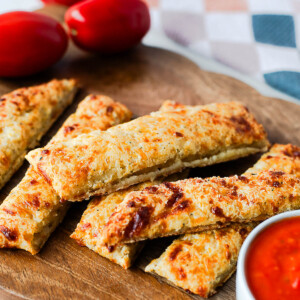 Crispy cottage cheese breadsticks served with marinara dipping sauce on a wooden board