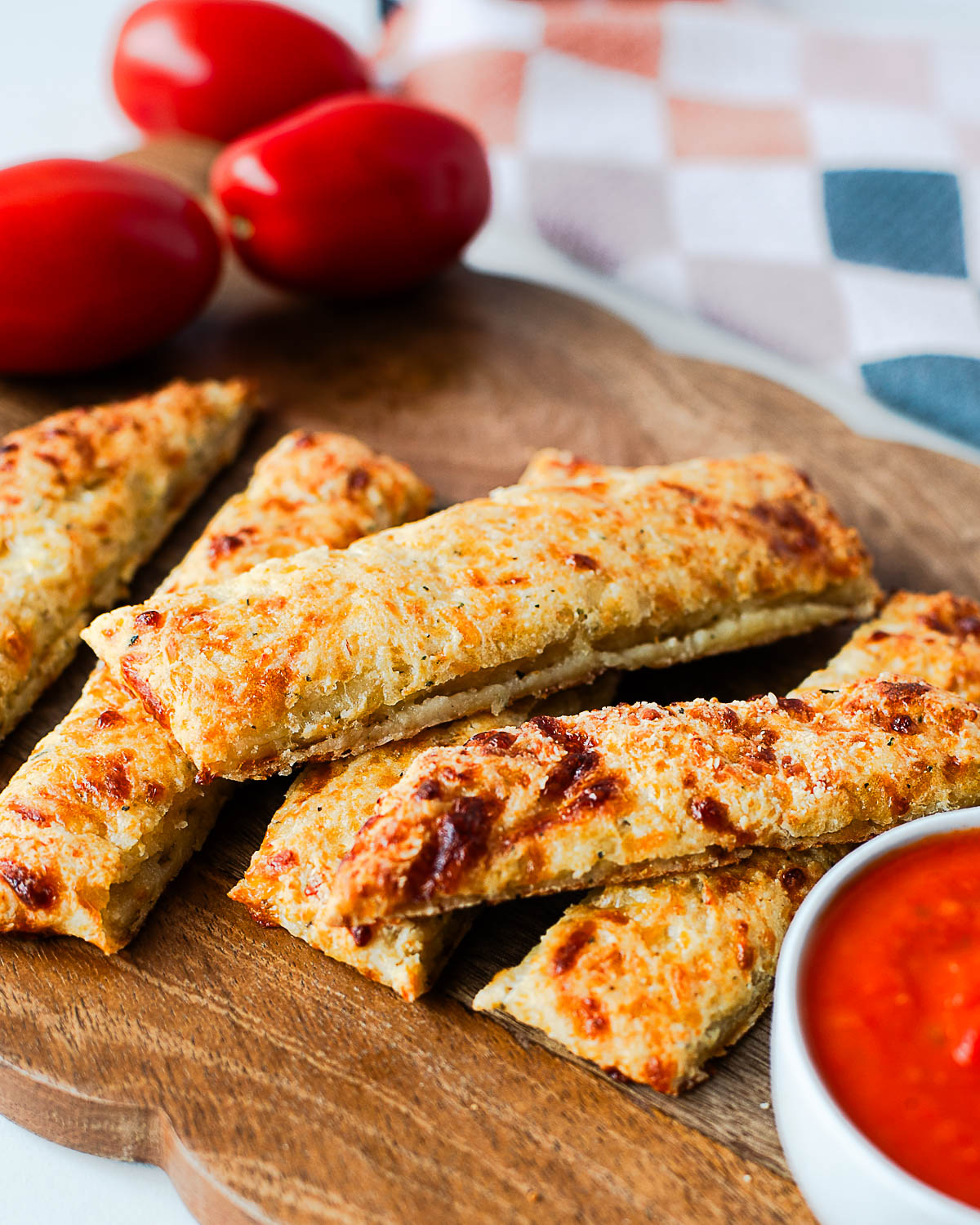 Crispy cottage cheese breadsticks served with marinara dipping sauce on a wooden board