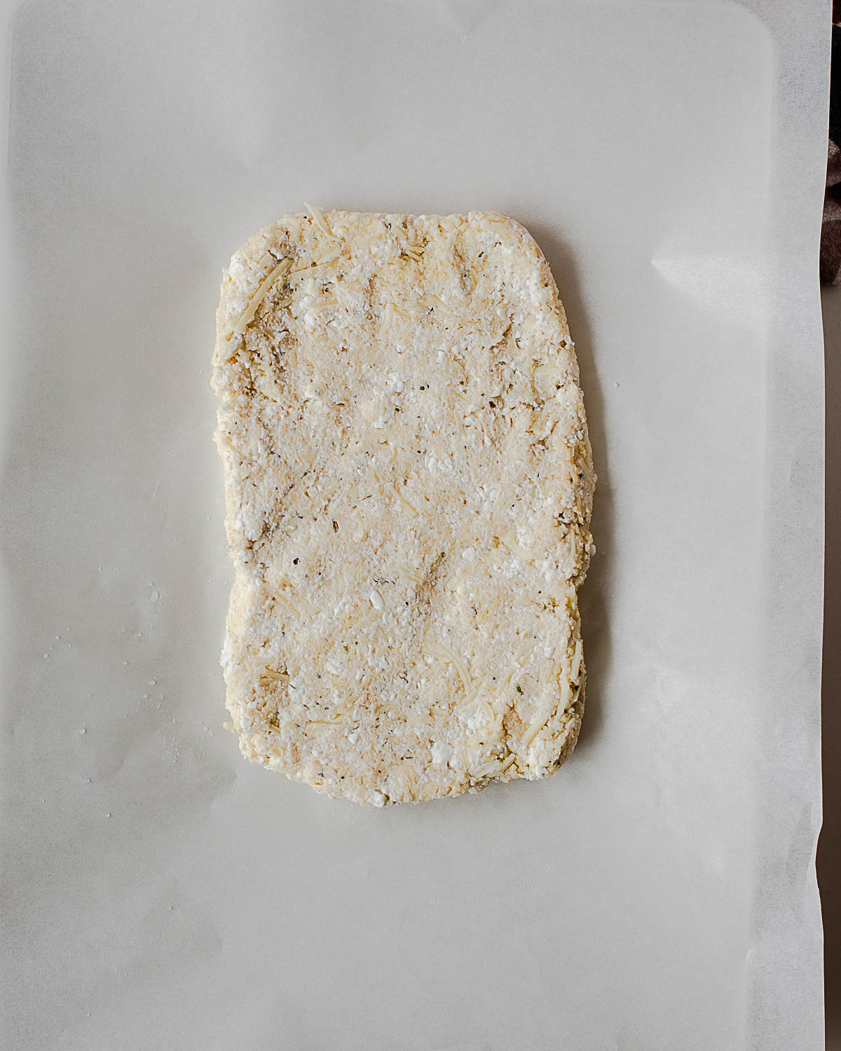 Shaped cottage cheese breadstick dough loaf on parchment paper, ready to bake