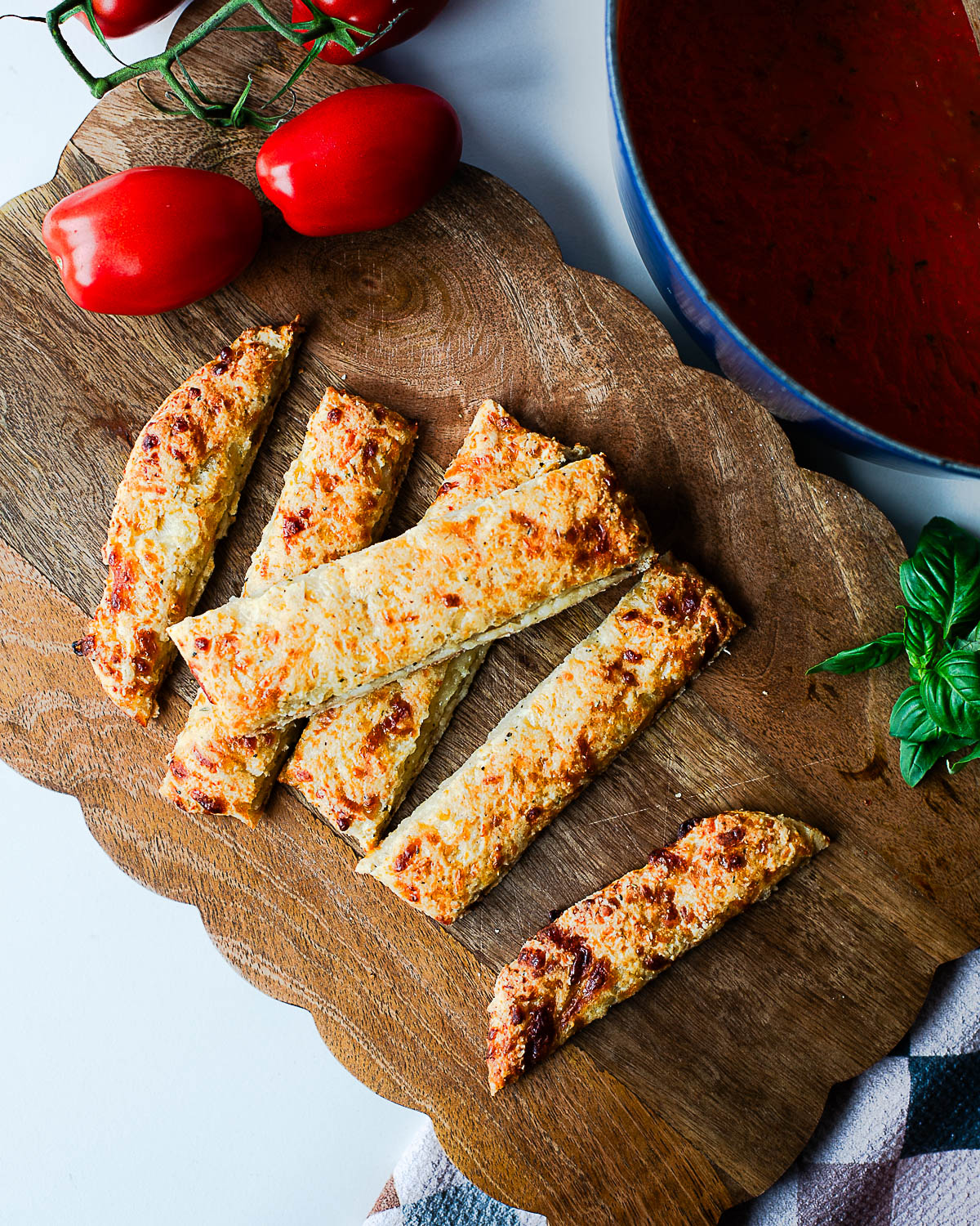 Overhead view of cheesy cottage cheese breadsticks with fresh tomatoes and basil