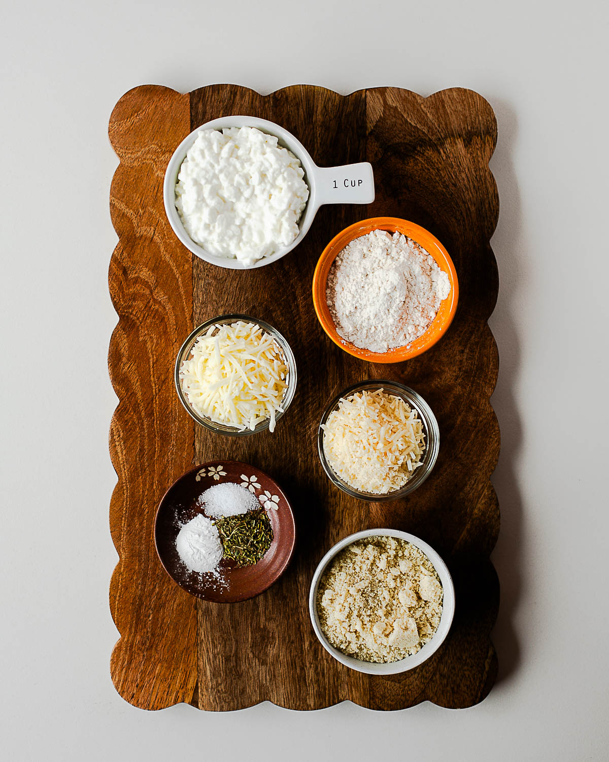 Flat lay of all ingredients for cottage cheese breadsticks measured and arranged on a wooden board