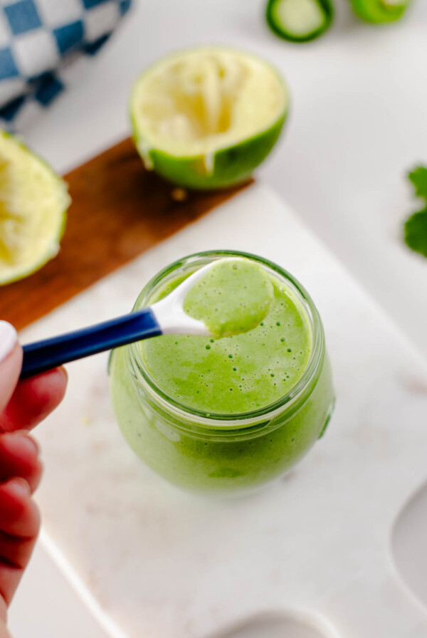 Spoon dipping into smooth cilantro jalapeño green taco sauce.