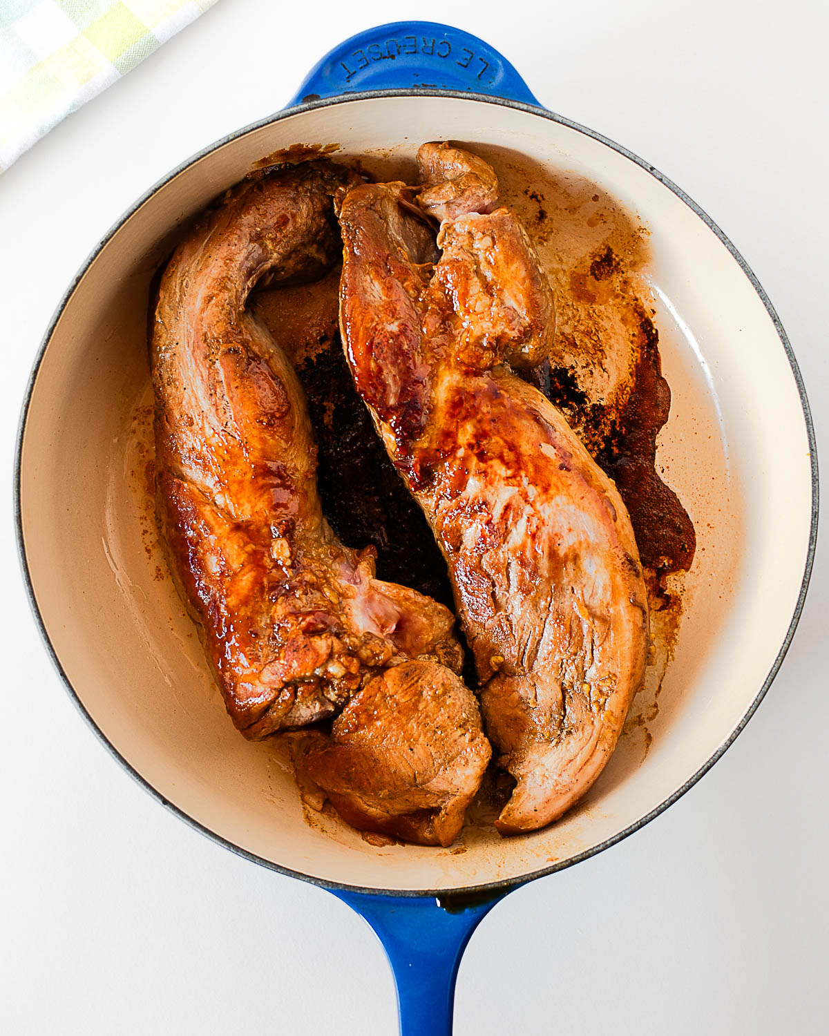 Pork tenderloins searing in a hot cast-iron skillet until golden brown on the outside to lock in juices.