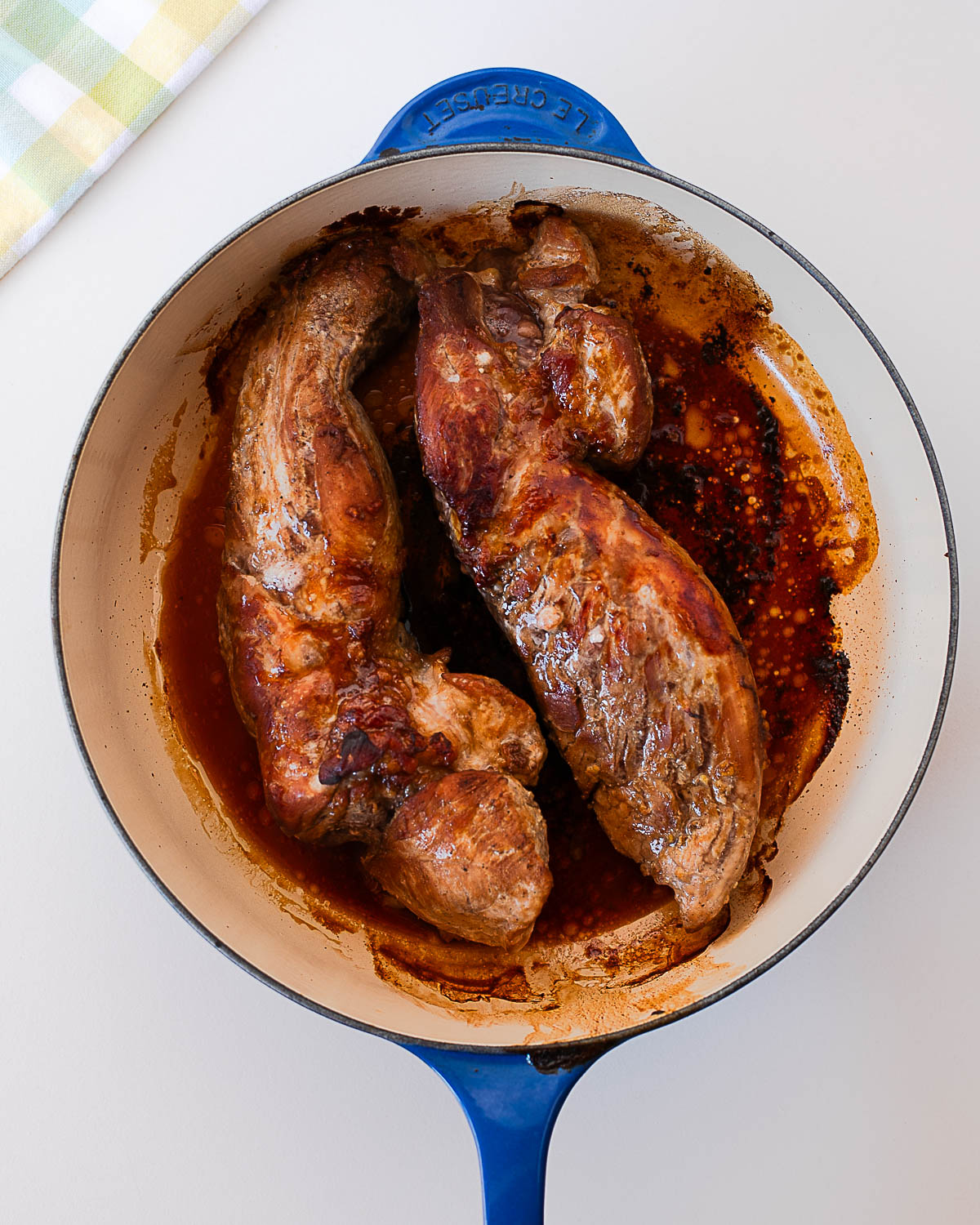 Asian marinated pork tenderloins roasting in the oven in a blue enamel Dutch oven with caramelized edges.