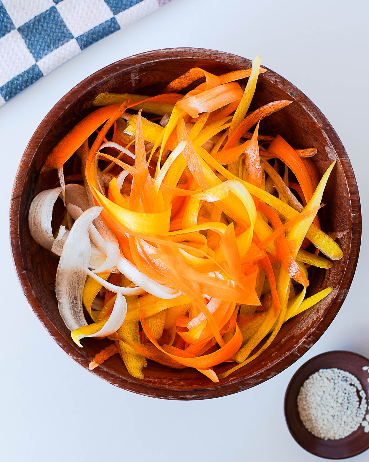 Freshly peeled rainbow carrot ribbons in a wooden bowl, ready for dressing with olive oil and rice vinegar