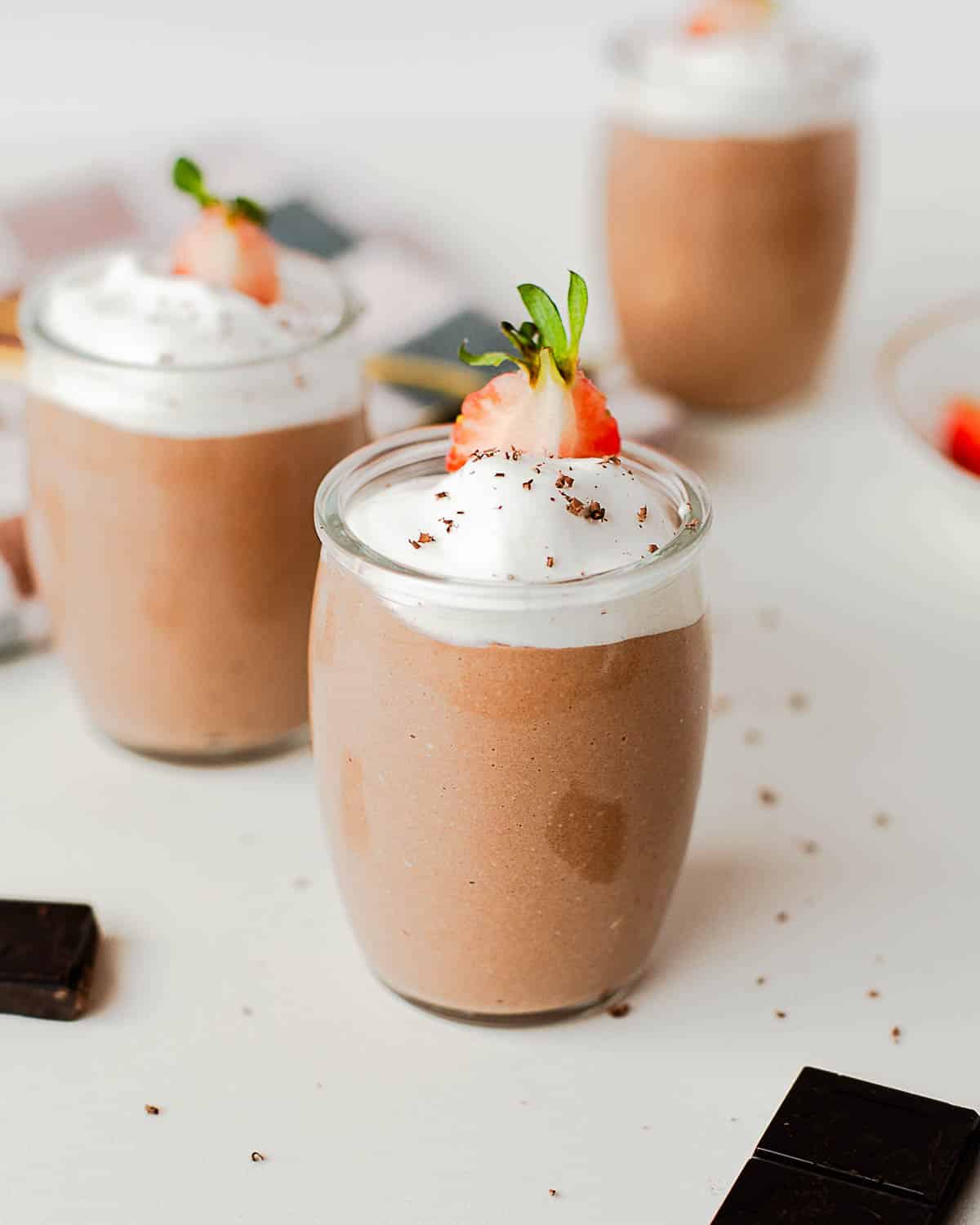 High protein cottage cheese chocolate pudding topped with whipped cream and a fresh strawberry in a glass jar.
