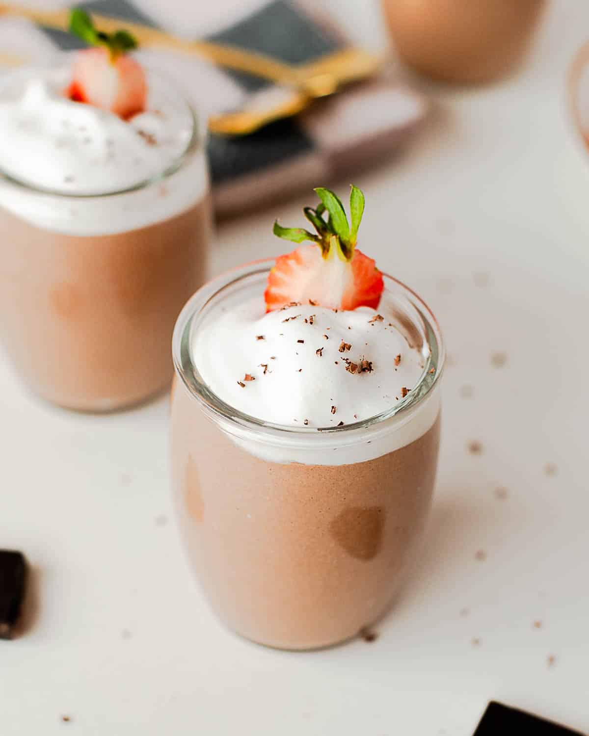 Chocolate cottage cheese pudding with creamy whipped topping and chocolate shavings in a small glass jar.