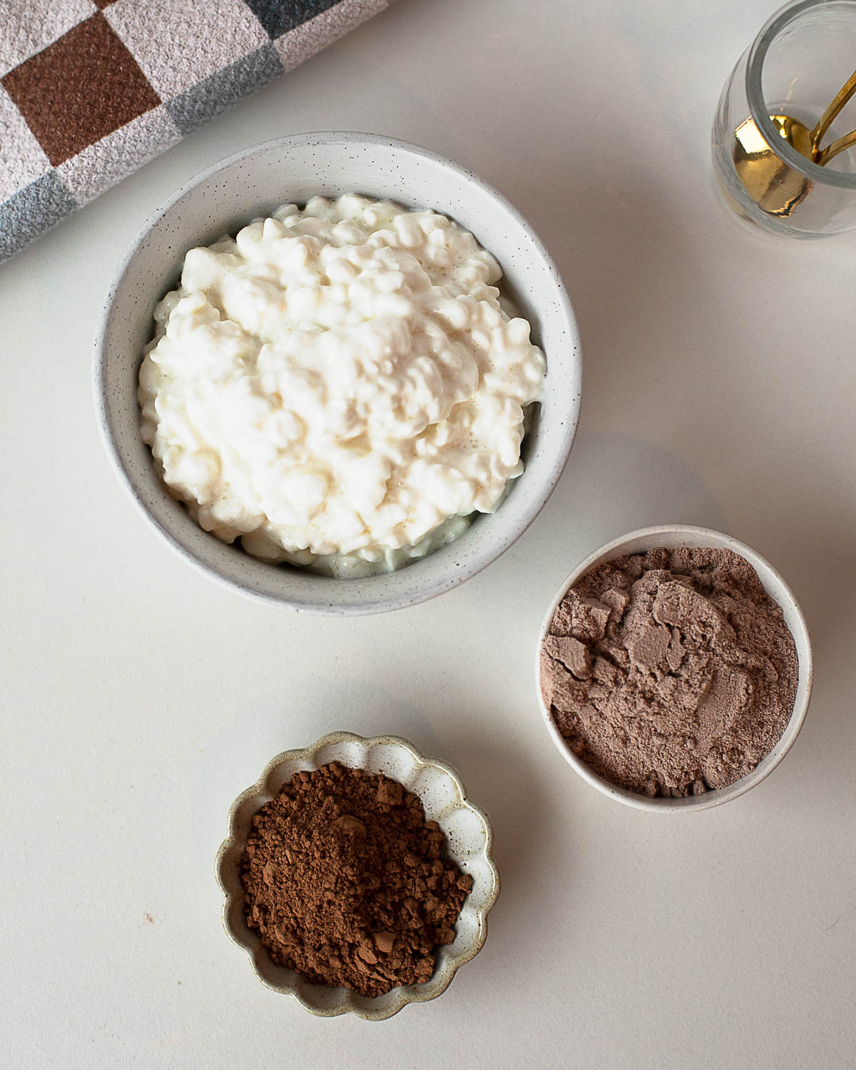 Ingredients for cottage cheese chocolate pudding including cottage cheese, cocoa powder, and chocolate protein powder.
