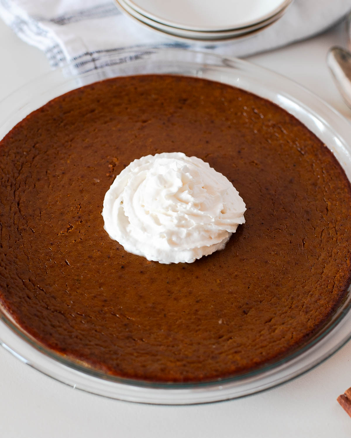 Crustless pumpkin pie topped with a swirl of dairy free whipped cream in the center of the pie dish.