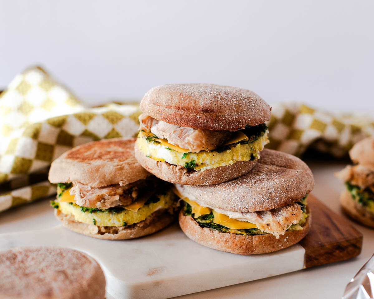 Leftover turkey breakfast sandwiches arranged on a marble board, made with spinach egg bake, cheddar, and English muffins.