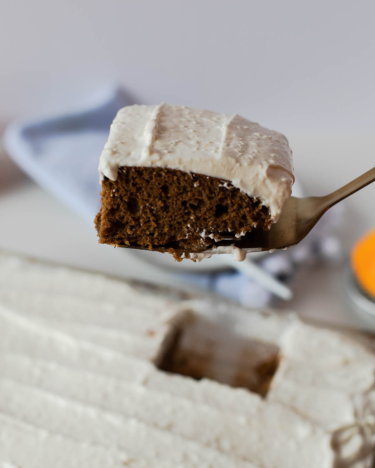 A slice of sweet potato sheet cake on a cake server, showing the soft texture and creamy layer of maple cream cheese frosting.