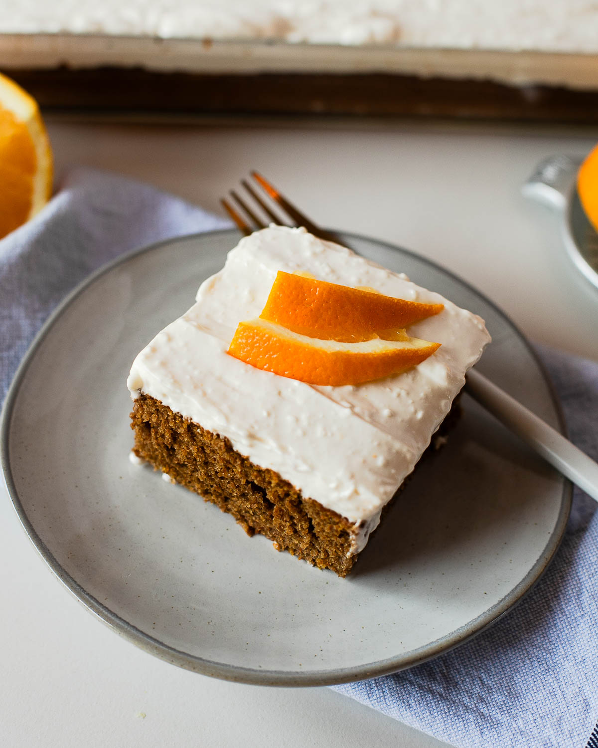 A single slice of sweet potato sheet cake on a plate, topped with orange zest curls and ready to enjoy.