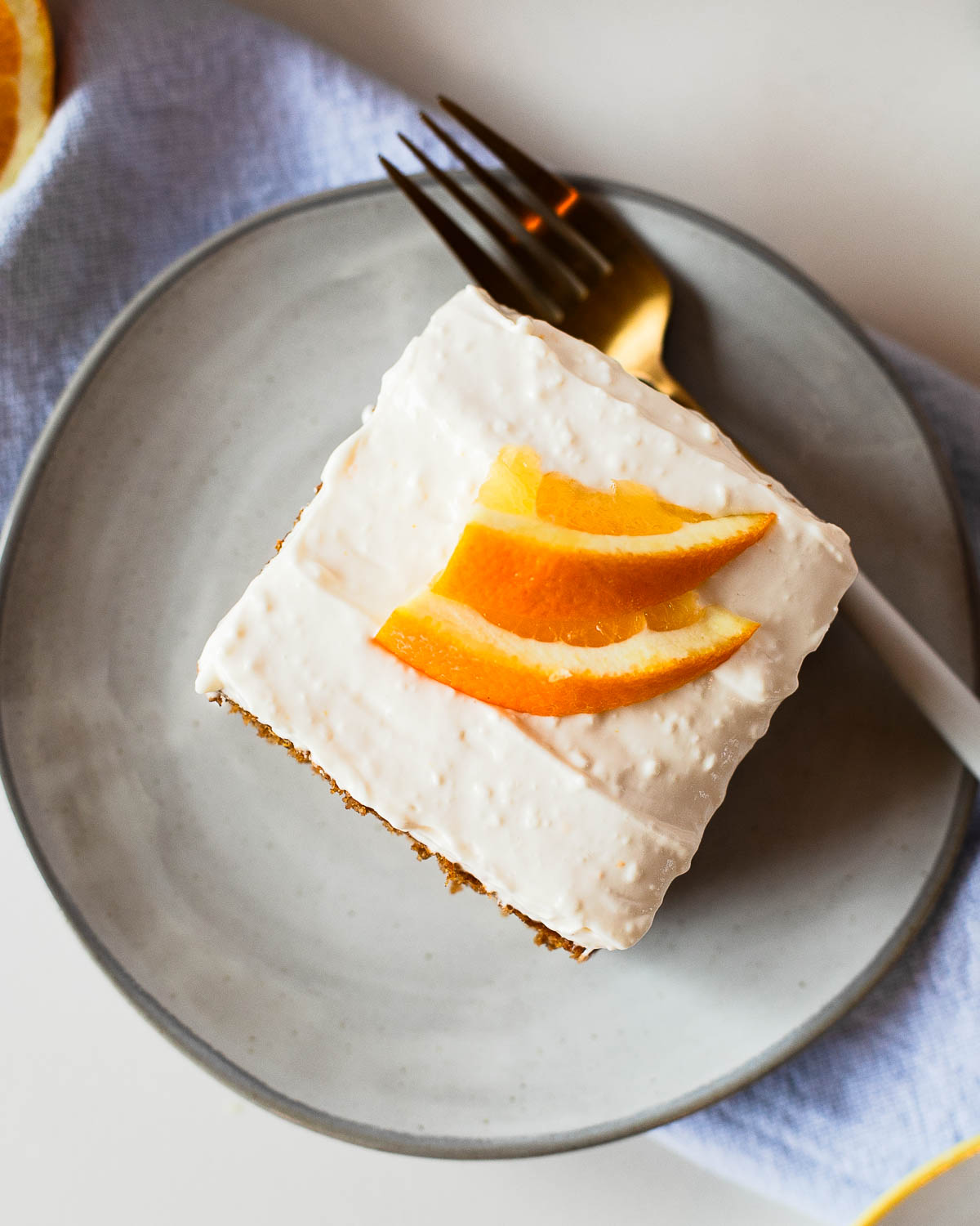Overhead view of a frosted sweet potato sheet cake slice with bright orange zest garnish on top.