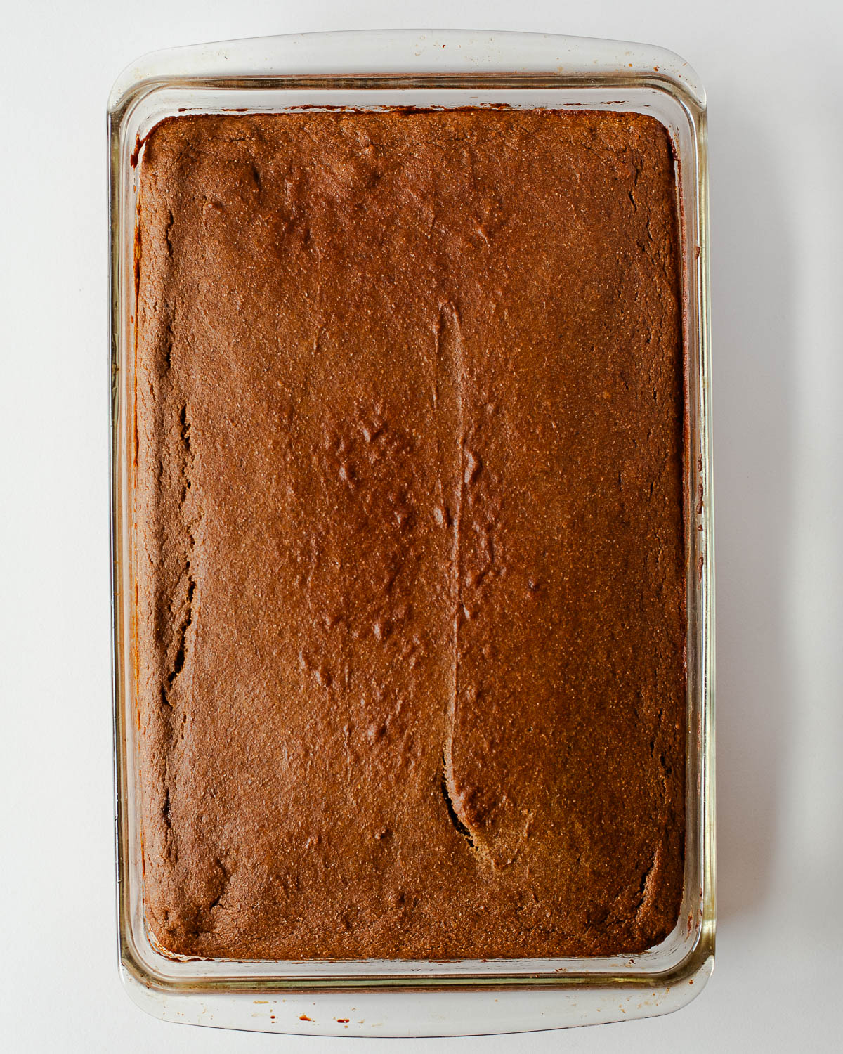 Freshly baked sweet potato sheet cake cooling in the pan, golden brown and slightly cracked on top.