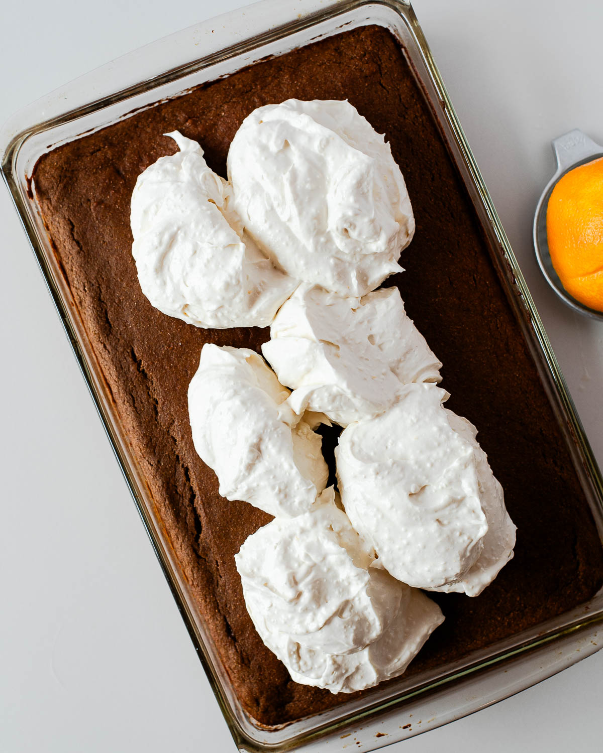 Large dollops of cream cheese frosting added on top of the baked sweet potato cake before spreading.