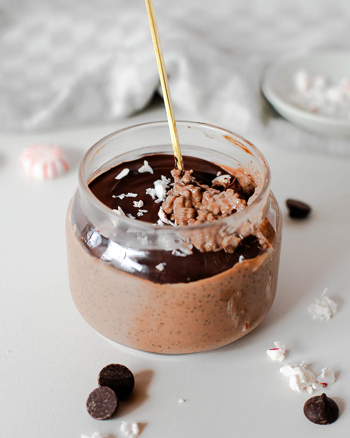 Spoon scooping creamy high-protein chocolate peppermint chia pudding from a glass jar