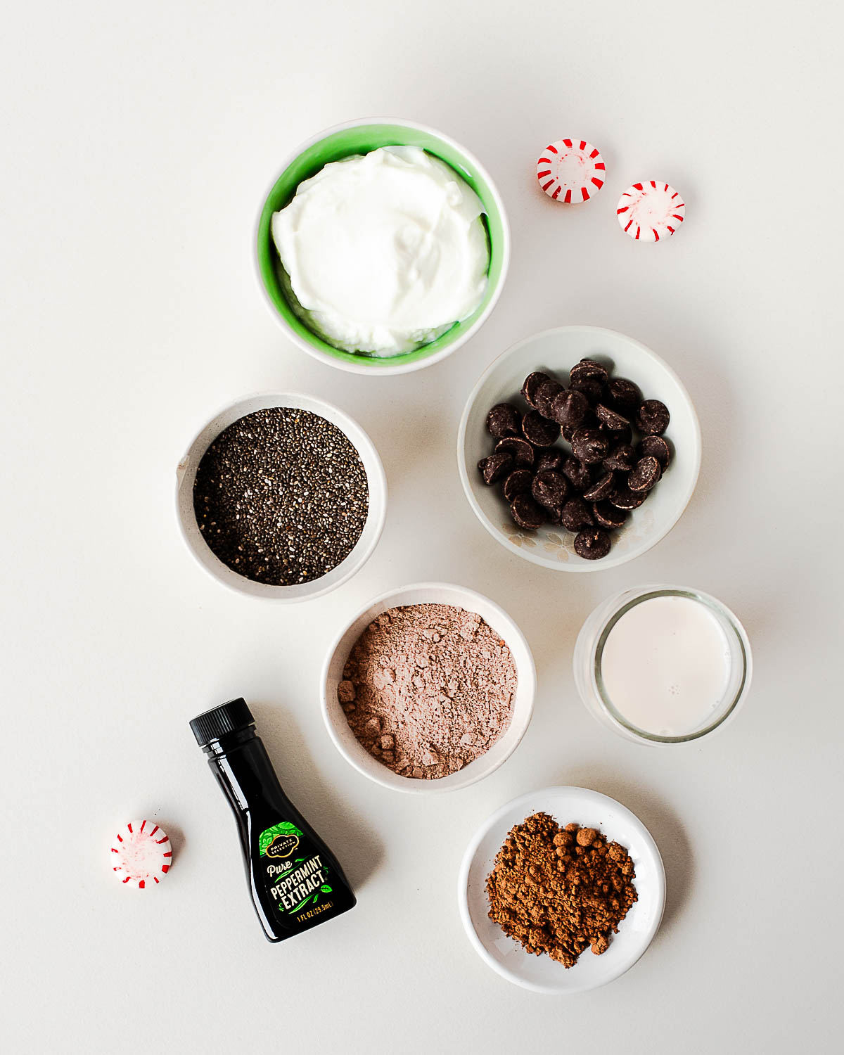 Ingredients for chocolate peppermint chia pudding including chia seeds, Greek yogurt, cocoa powder, protein powder, and peppermint extract